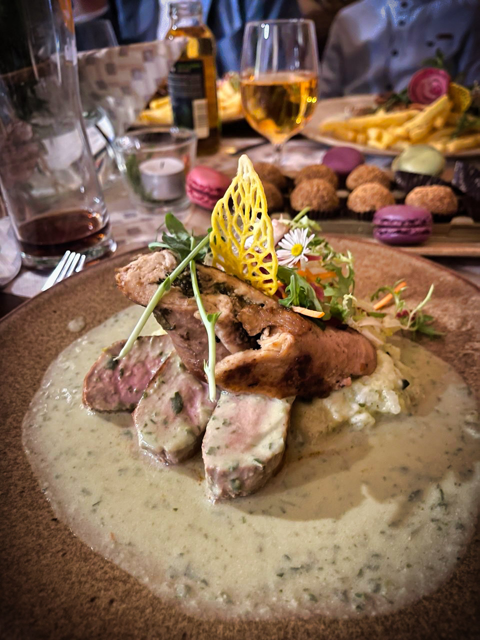 Gurmánske hlavné jedlo s mäsom, bylinkami a umeleckou žltou dekoráciou, v pozadí macaróny