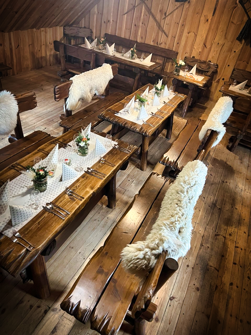 Tradičné prestieranie s drevenými stolmi, bielymi ovčími kožušinami a kvetinovými dekoráciami