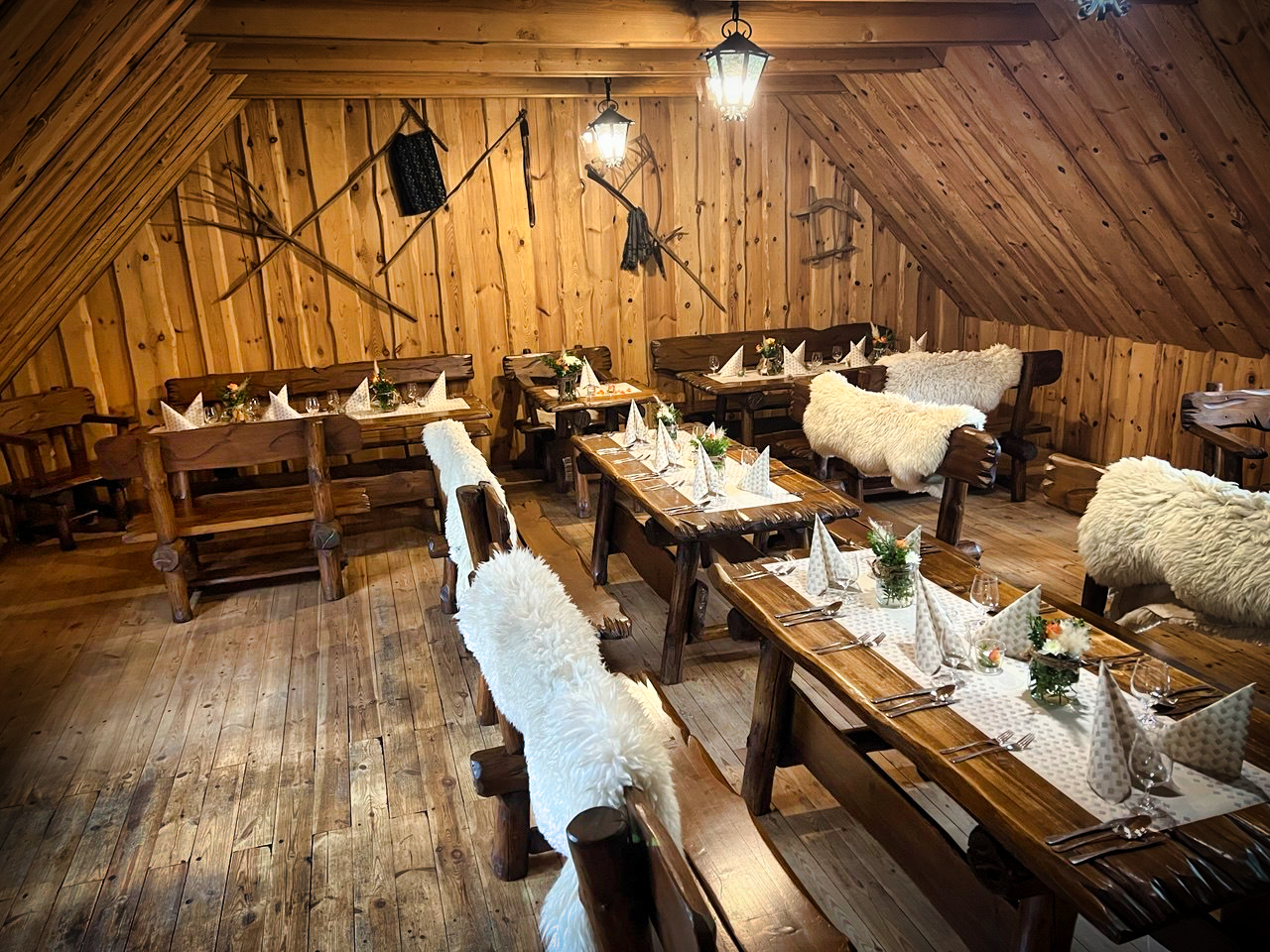 Horná jedáleň s tradičnými drevenými stolmi, ovčími kožušinami a poľovníckymi dekoráciami na stenách