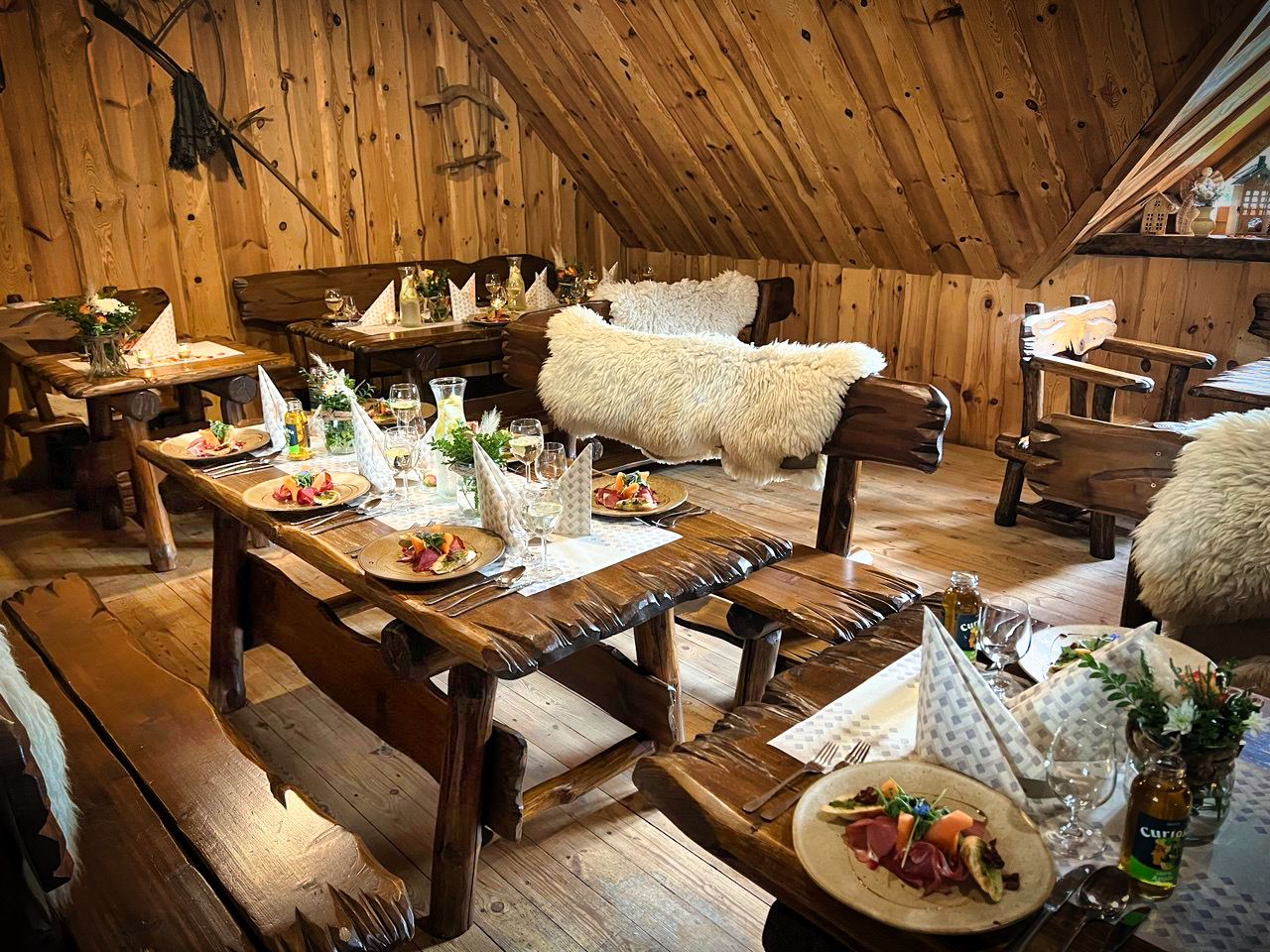 Horná jedáleň počas servírovania s prestretými stolmi, vínom a gurmánskymi predkrmami